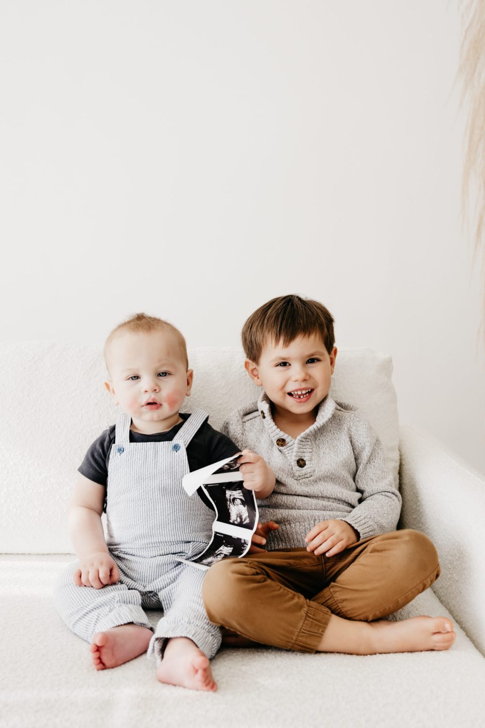 Elizabeth-McCravy-Baby-Announcement-Studio-Photos-27 two boys holding sonogram of baby #3